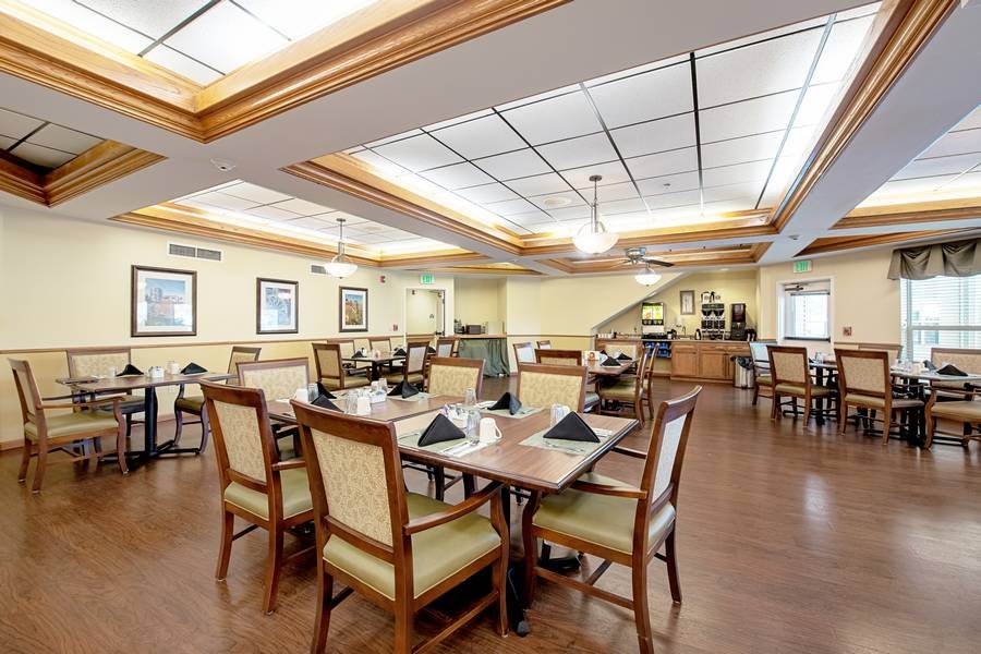 An elegant dining room with neatly arranged tables and chairs, featuring warm lighting and tasteful decor.