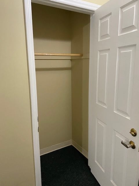 An empty closet with a wooden rod and an open door.