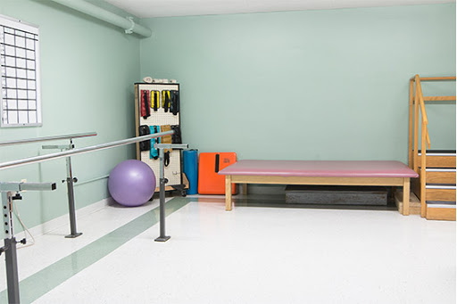 A well-equipped rehabilitation space with exercise equipment, including a stability ball and therapy table.