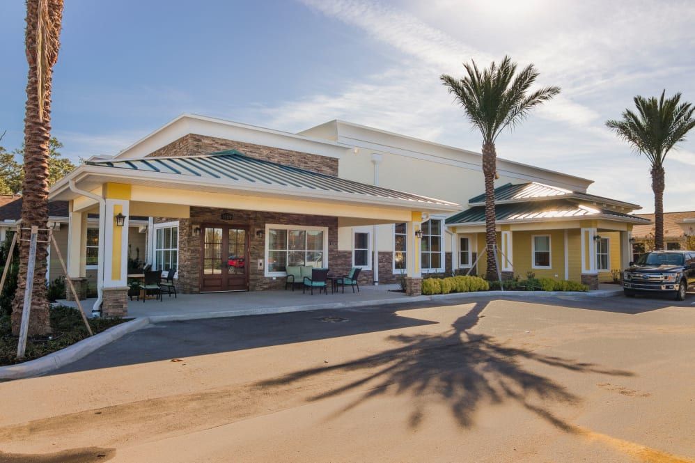 A sunny view of a building entrance with a palm tree casting a shadow.