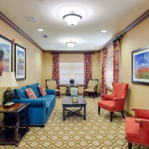 A well-decorated living room featuring a blue sofa, two red armchairs, and artwork on the walls.