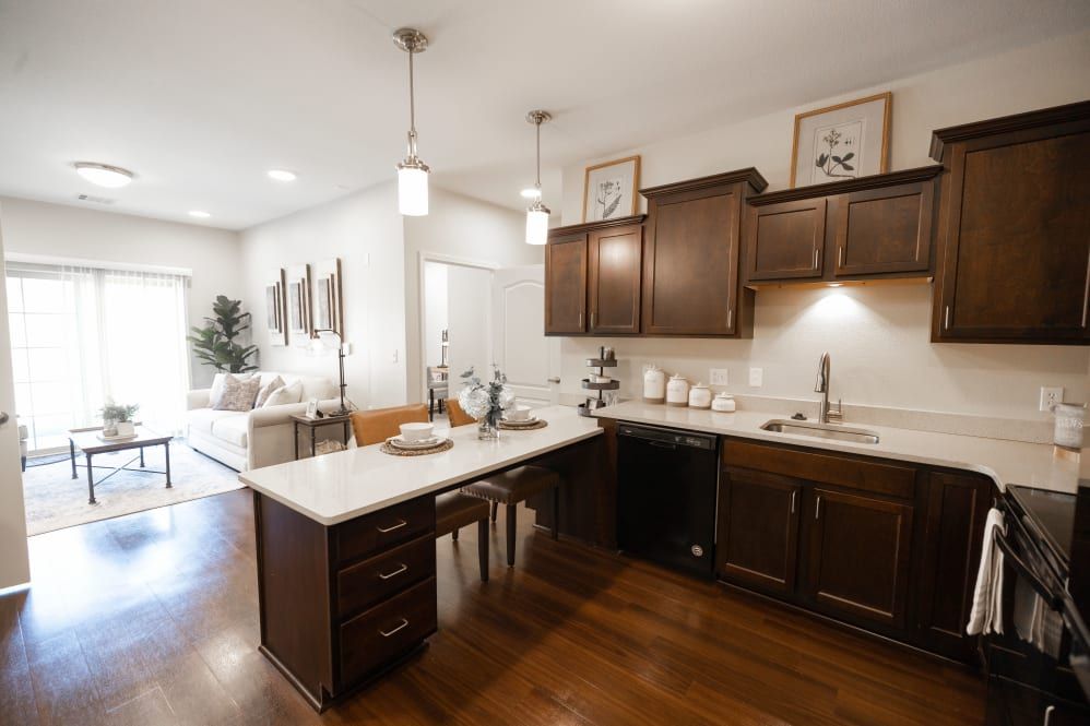 A modern kitchen with dark wood cabinets and a central island, featuring pendant lighting and an open layout.