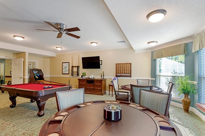 A cozy game room featuring a pool table, poker table, and a television.