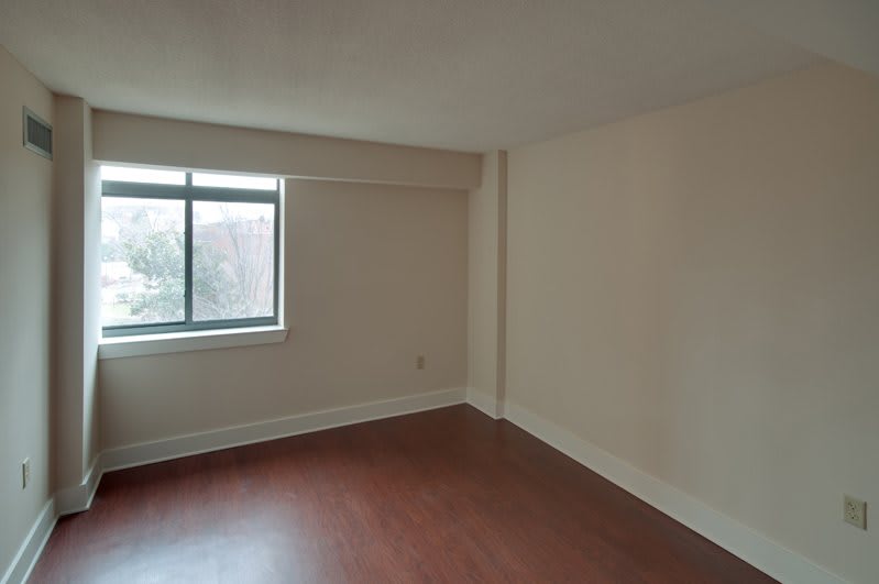 An empty room with a hardwood floor and a large window.