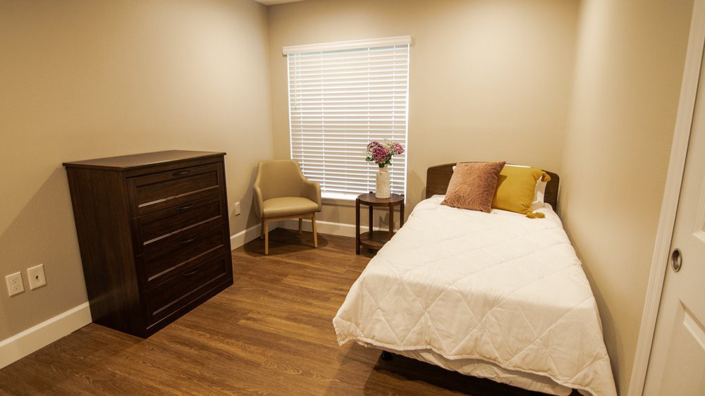 A cozy bedroom with a bed, dresser, and soft lighting.