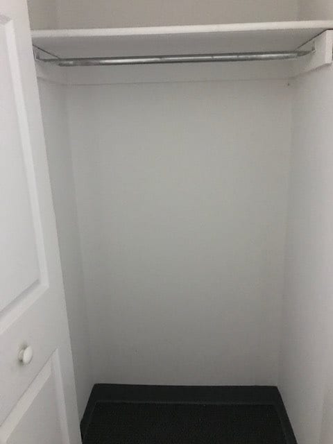An empty closet with a single rod for hanging clothes.