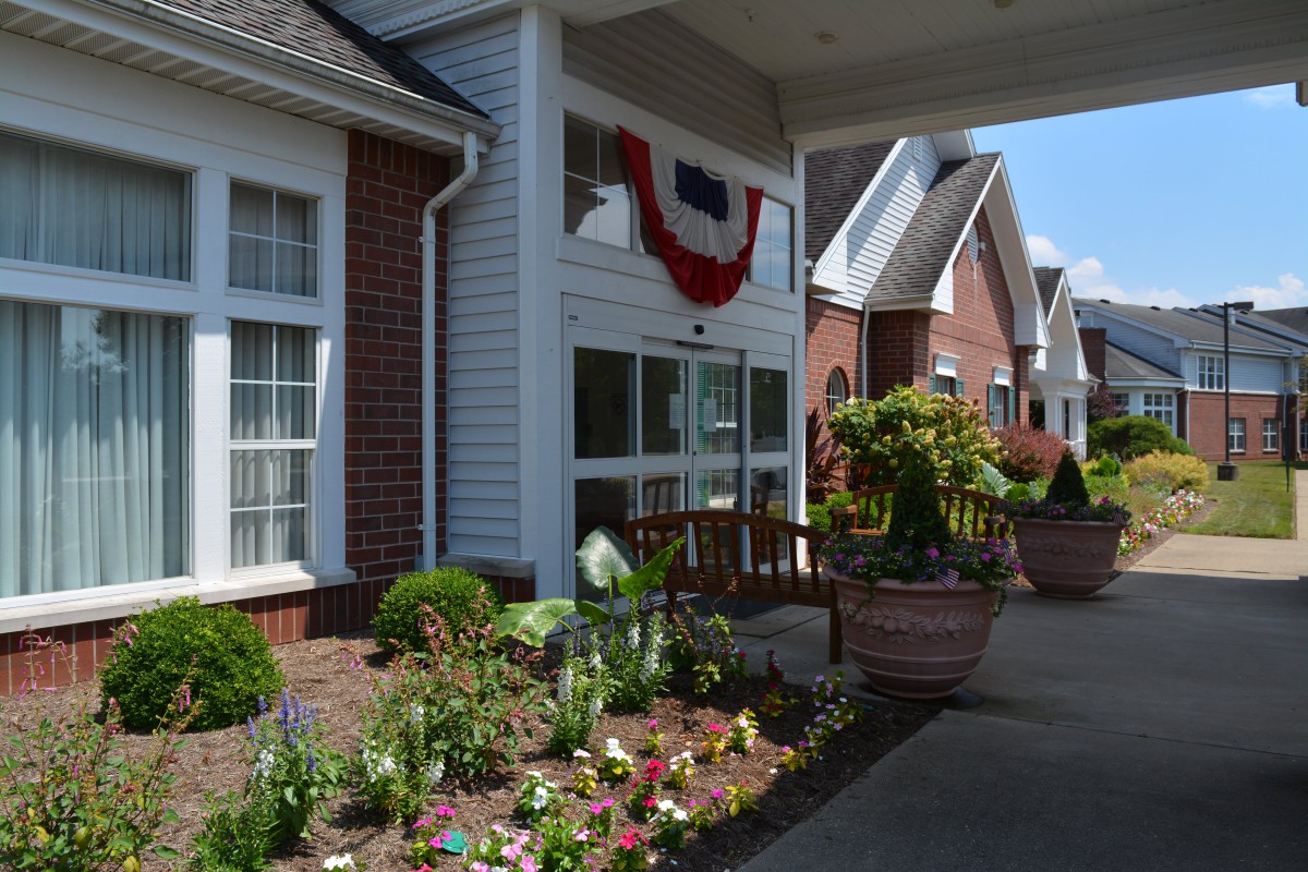A welcoming building entrance with a garden and flowers.