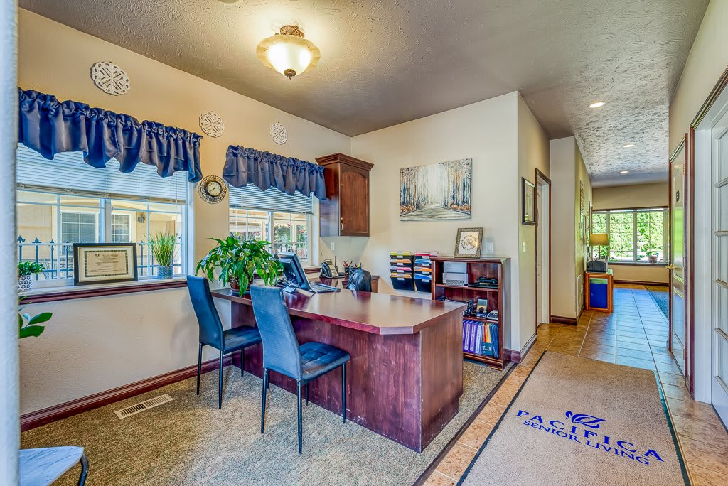 A cozy office space with a desk and chairs, decorated with plants and artwork.