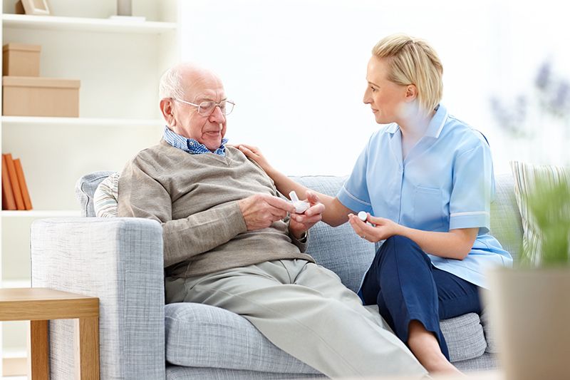 A caregiver assisting an elderly man at home.