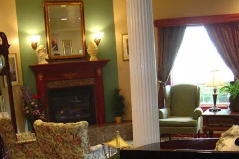 A cozy living room with a fireplace, elegant furniture, and a decorative column.
