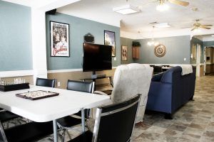 A cozy living room with a television, comfortable seating, and artwork on the walls.