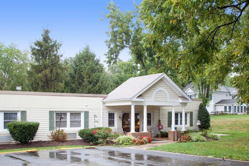 A quaint residential house with a porch surrounded by greenery.