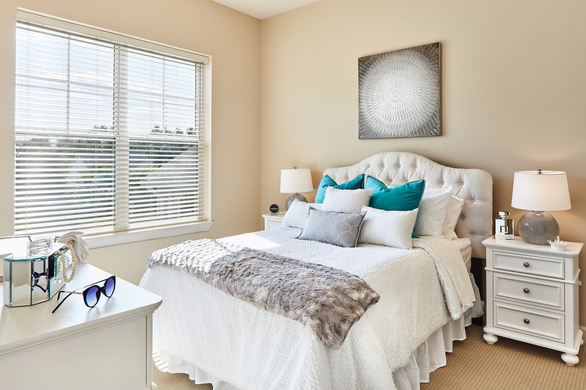 A bright and cozy bedroom featuring a modern bed with decorative pillows and ample natural light.
