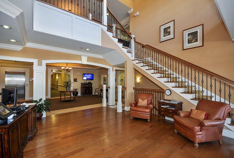 A spacious lobby area featuring a grand staircase and elegant wooden flooring.
