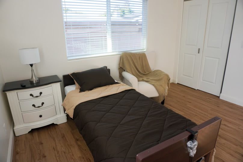 A minimalist bedroom with a single bed, chair, and window.