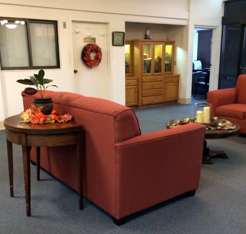 A cozy living room with red sofas, a round wooden table, and decorative items.