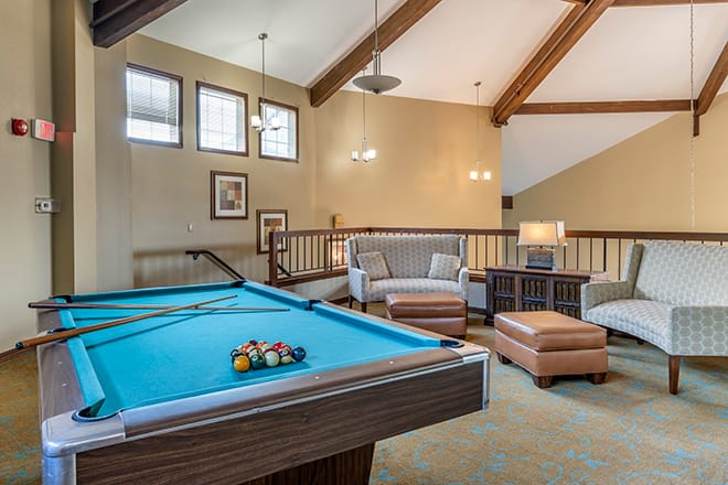 A cozy game room featuring a pool table and comfortable seating area.