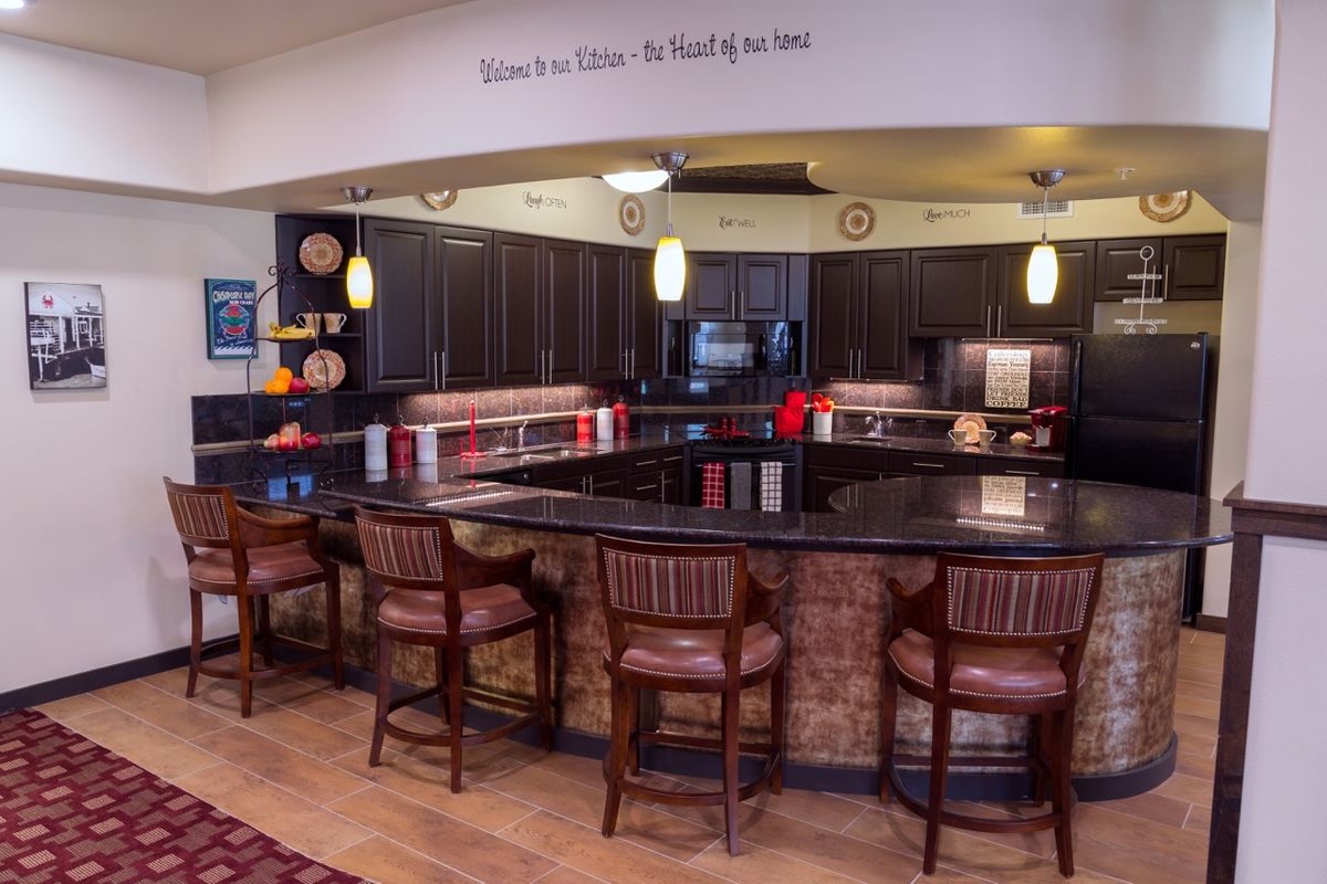 A cozy kitchen interior featuring a counter with stools and pendant lighting.