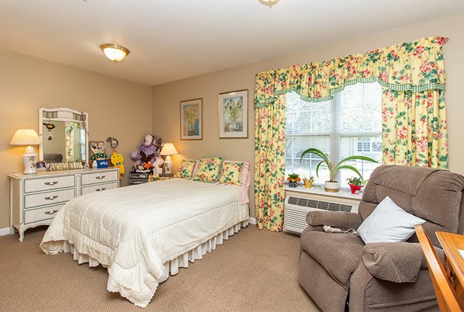 A cozy bedroom with floral curtains and a neatly made bed.