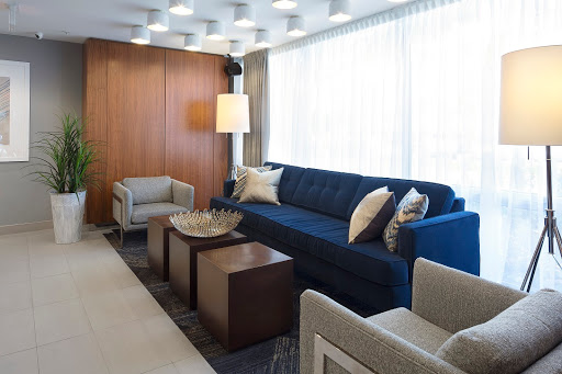 A modern living room featuring a blue sofa, coffee tables, and ample natural light.
