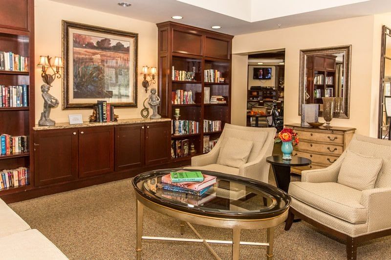 A cozy living room featuring elegant furniture, a bookshelf filled with books, and a beautiful piece of artwork on the wall.