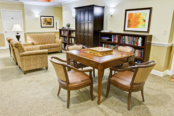 A cozy interior with a table, chairs, bookshelves, and artwork.