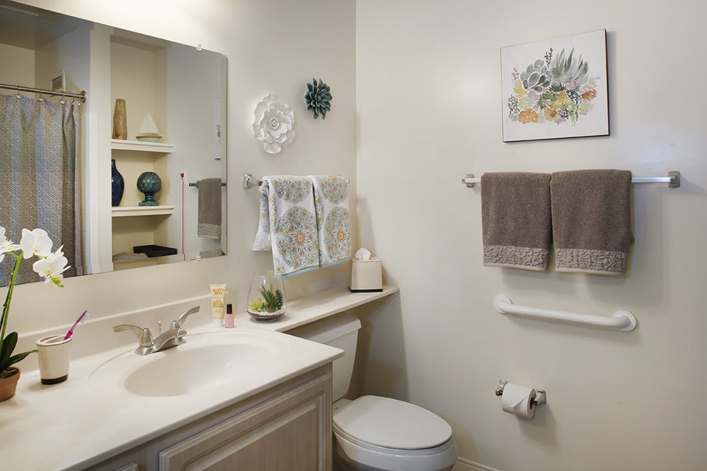 A neatly organized bathroom with a sink, mirror, and decorative elements.