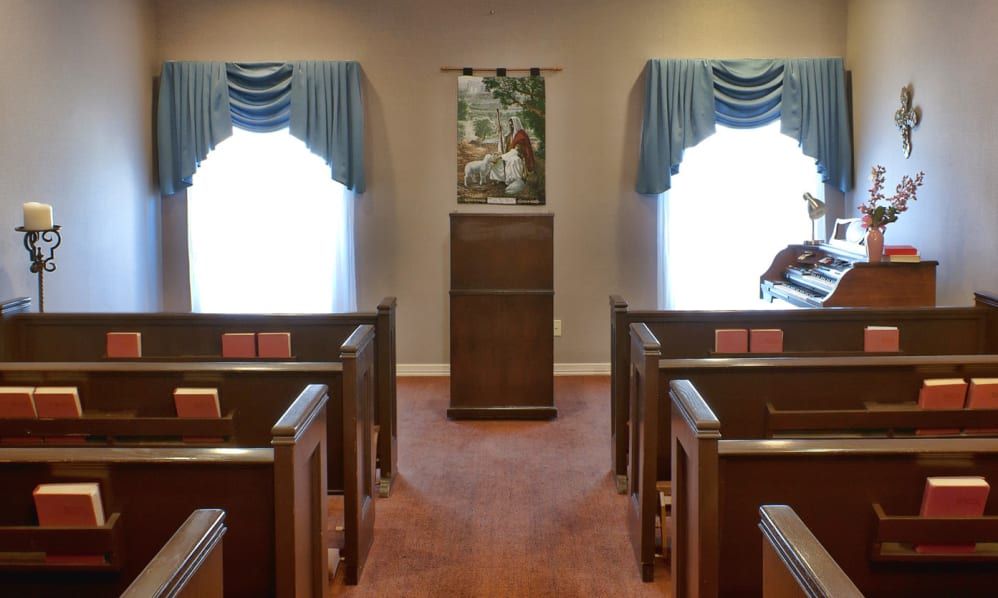An interior view of a small chapel with wooden pews and a central pulpit.