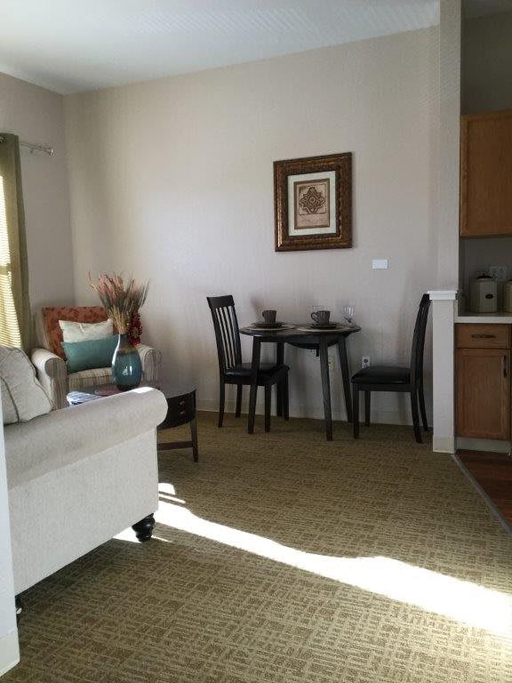 A cozy living area with a small dining table and chairs, accented by a comfortable sofa and decorative elements.