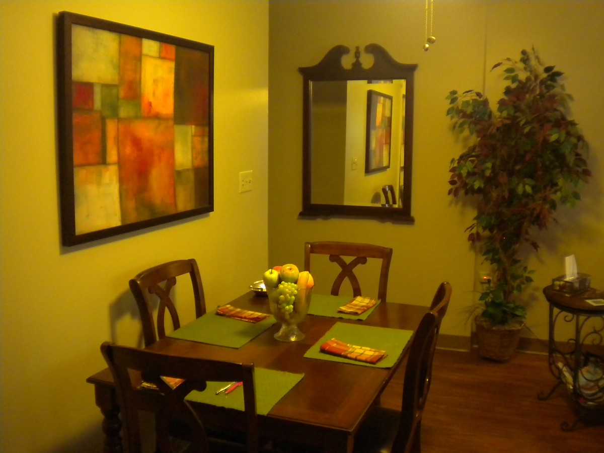 A cozy dining area with a wooden table and chairs, complemented by wall art, a mirror, and decorative plants.