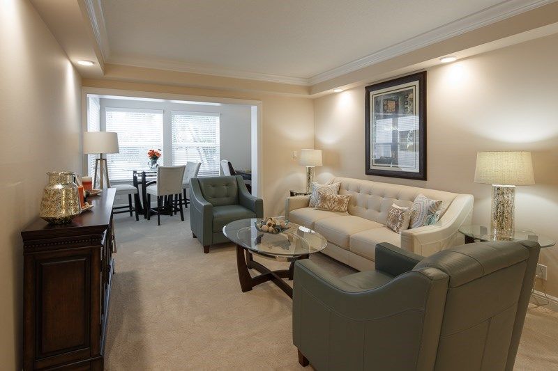 A cozy living room with a comfortable sofa, armchairs, and a dining area in the background.