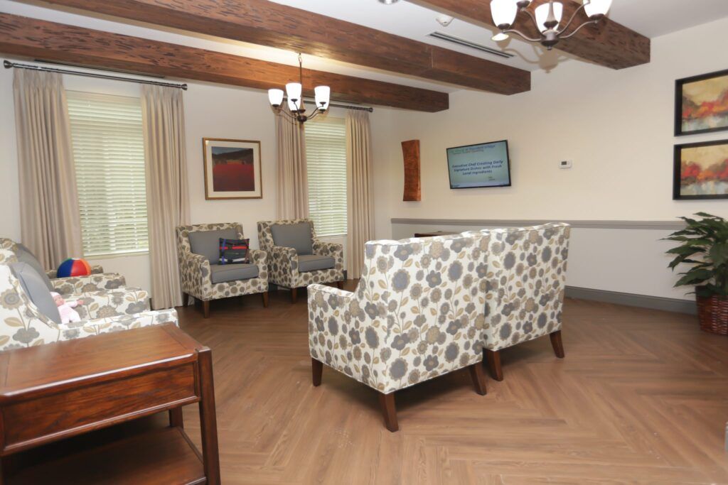 A cozy living room with patterned furniture and wooden ceiling beams.