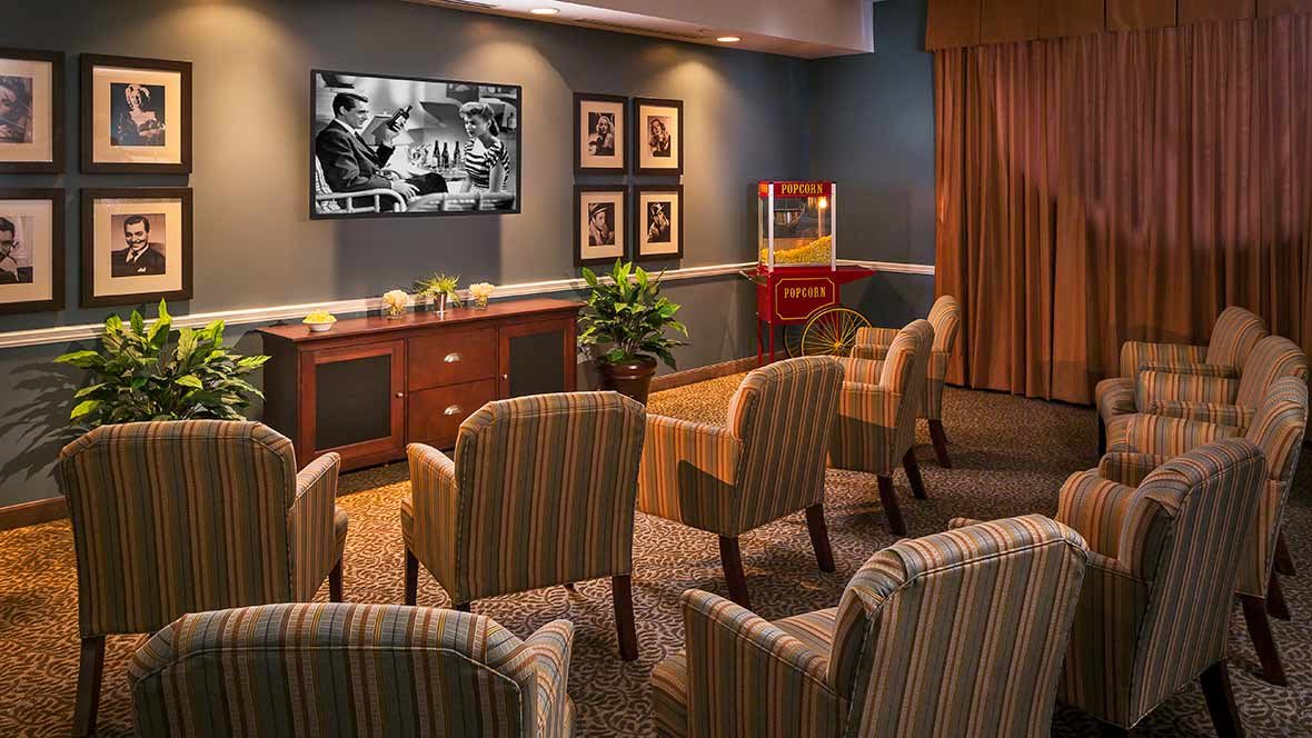 A cozy home theater setup with striped chairs, a mounted TV, and a popcorn machine.