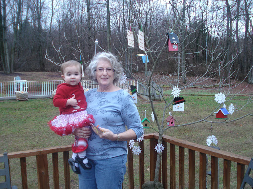 A joyful moment shared between a child and an adult, surrounded by festive decorations on a tree.