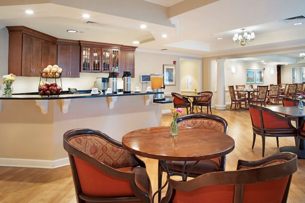 A cozy lounge area with wooden tables and chairs, featuring warm lighting and elegant decor.