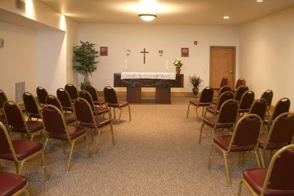 A small chapel with rows of chairs facing an altar.