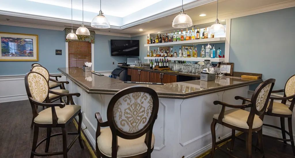 A stylish bar interior with a well-stocked shelf, elegant chairs, and ambient lighting.