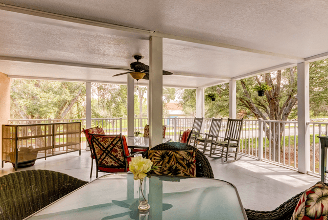 A cozy covered patio featuring comfortable seating and a view of the surrounding greenery.