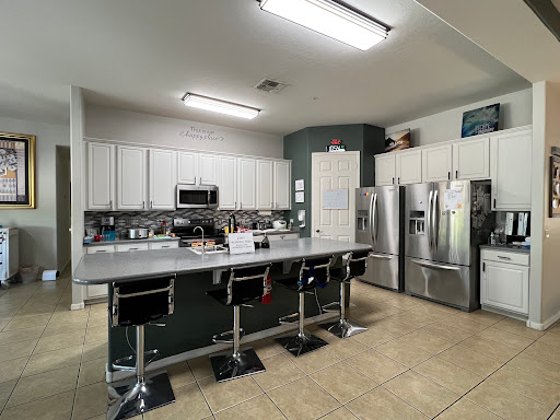 A modern kitchen featuring a spacious island with bar stools, stainless steel appliances, and white cabinetry.