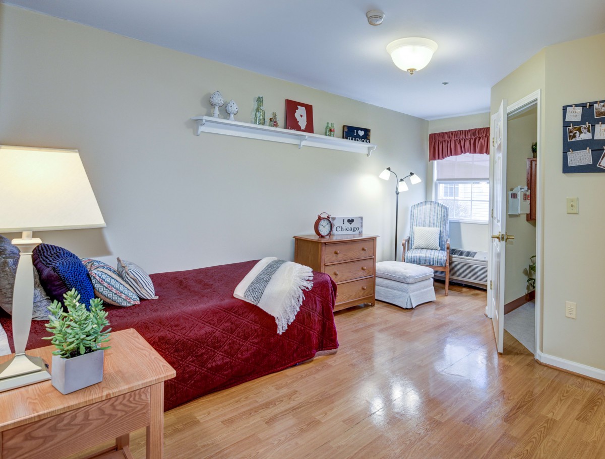 A cozy living room with a red sofa, wooden furniture, and decorative items on a shelf.