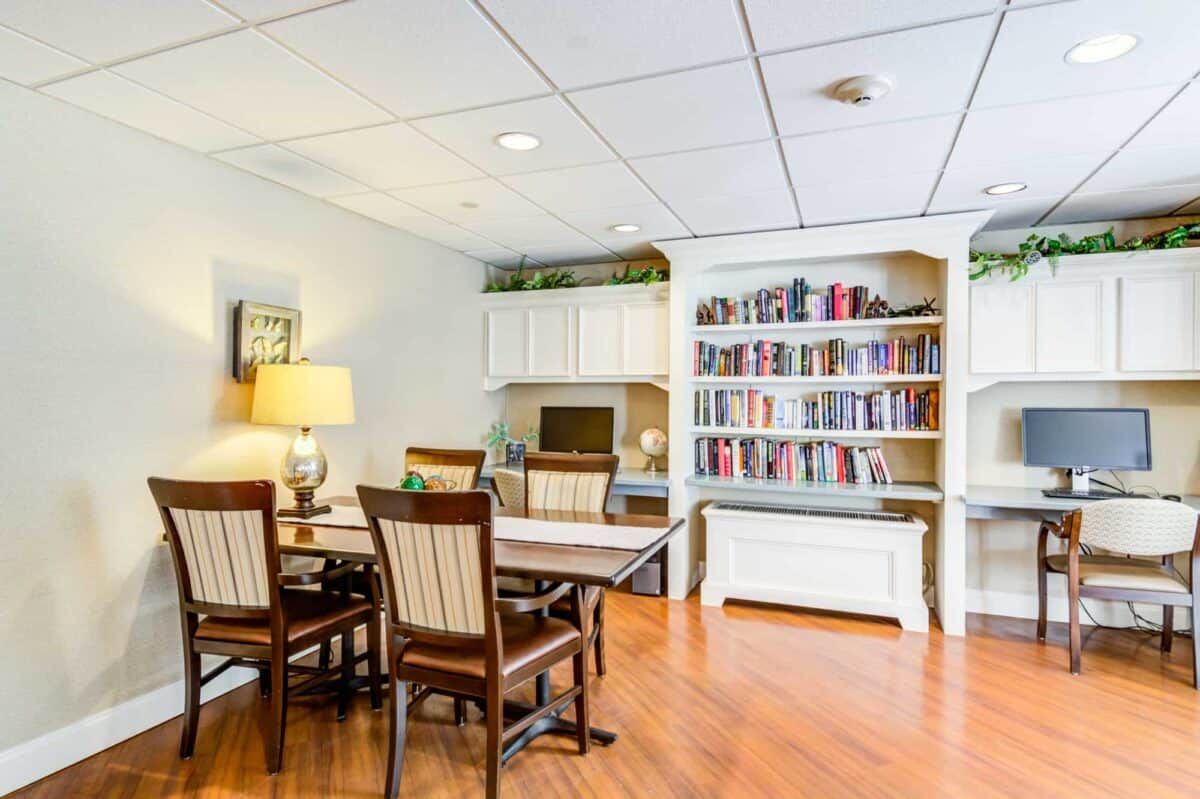 A well-organized office space featuring a table with chairs, a desk, and a bookshelf filled with books.