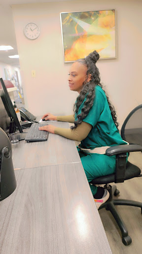 A dedicated healthcare worker focused on her tasks at a computer desk.