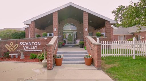 A welcoming entrance to a community building, showcasing brick architecture and beautiful landscaping.