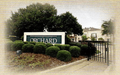 Entrance sign to the Orchard gated community surrounded by greenery.