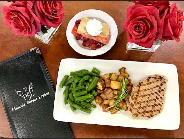 A beautifully presented meal with grilled meat, green beans, roasted potatoes, and a dessert on the side.