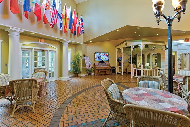 A spacious lobby with international flags, wicker furniture, and a large television.