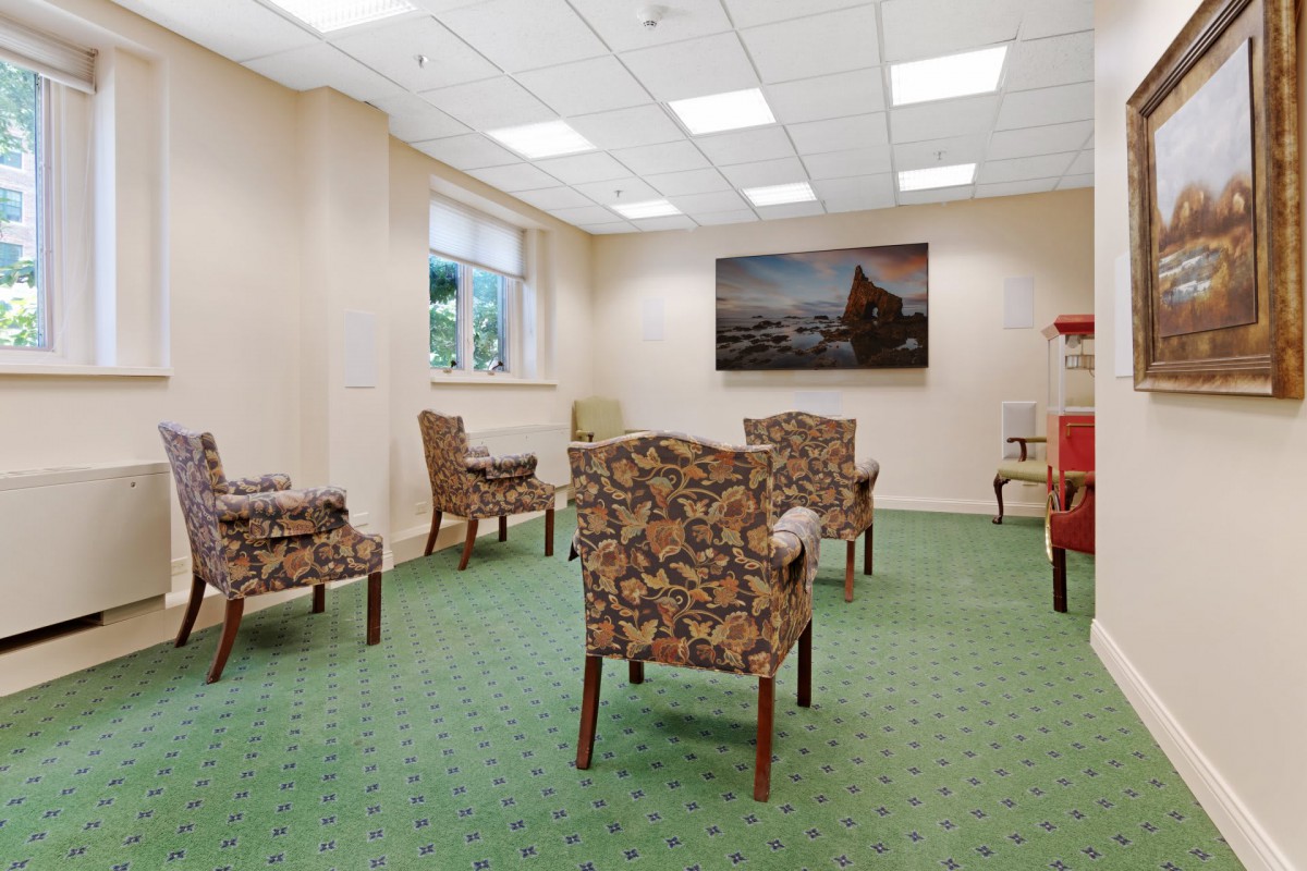 A well-lit waiting room with patterned chairs and a green carpet.
