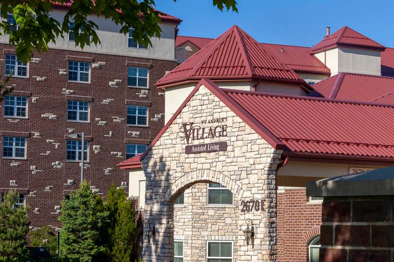 A modern apartment complex with a stone facade and red roof under a clear blue sky.