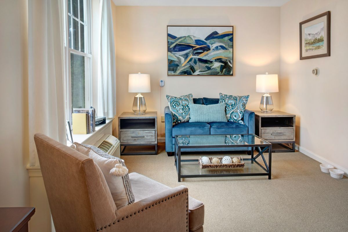 A cozy living room with a blue sofa, abstract artwork, and modern decor.