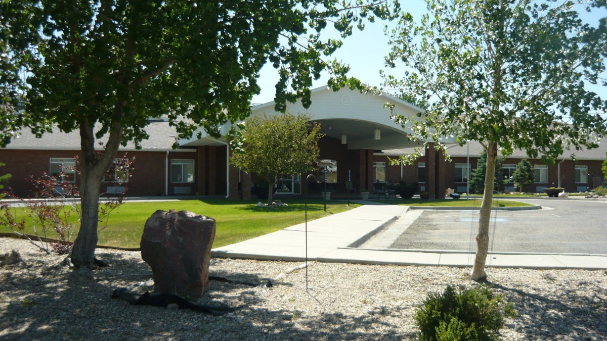 A view of a building with an entrance surrounded by trees and landscaping.